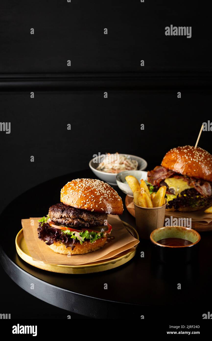 Deux savoureux cheeseburger et pommes de terre frites sur table sombre Copy space Banque D'Images