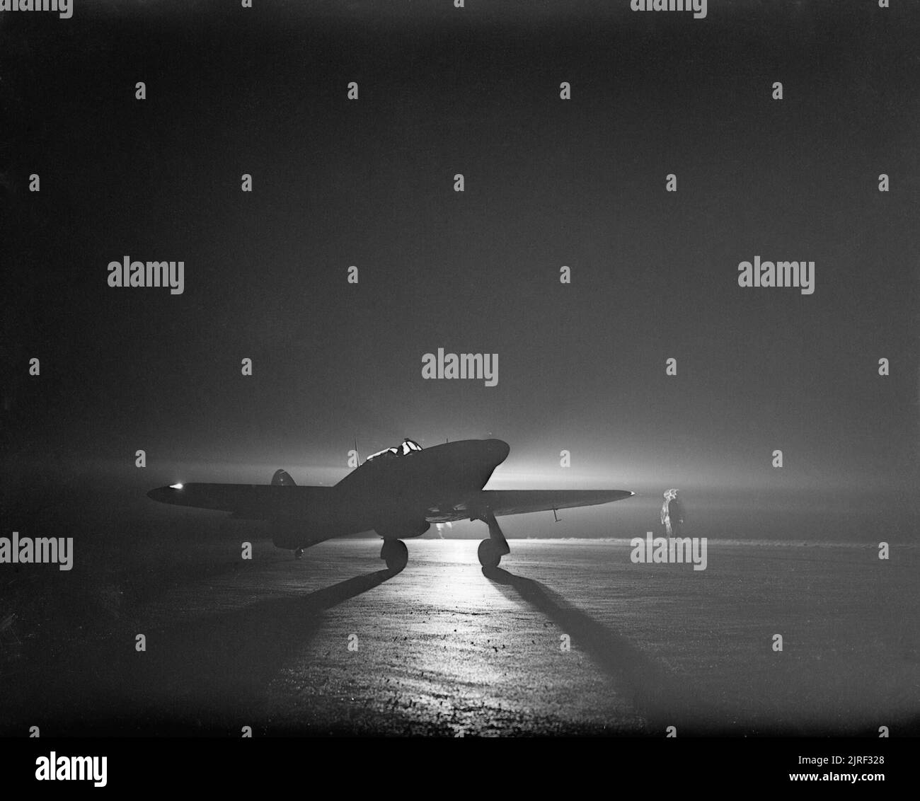 Un Hawker Hurricane Mk I de n° 85 Squadron roulait par la lumière de la torche à Debden, avant de décoller pour intercepter les voleurs de nuit, 14 mars 1941. Un Hawker Hurricane Mark I de chasse nocturne n° 85 Squadron RAF le roulage par la lumière de la torche à Debden, Essex, avant de décoller pour intercepter les voleurs de nuit. Remarque les feux de navigation sur les extrémités de l'aile. Banque D'Images