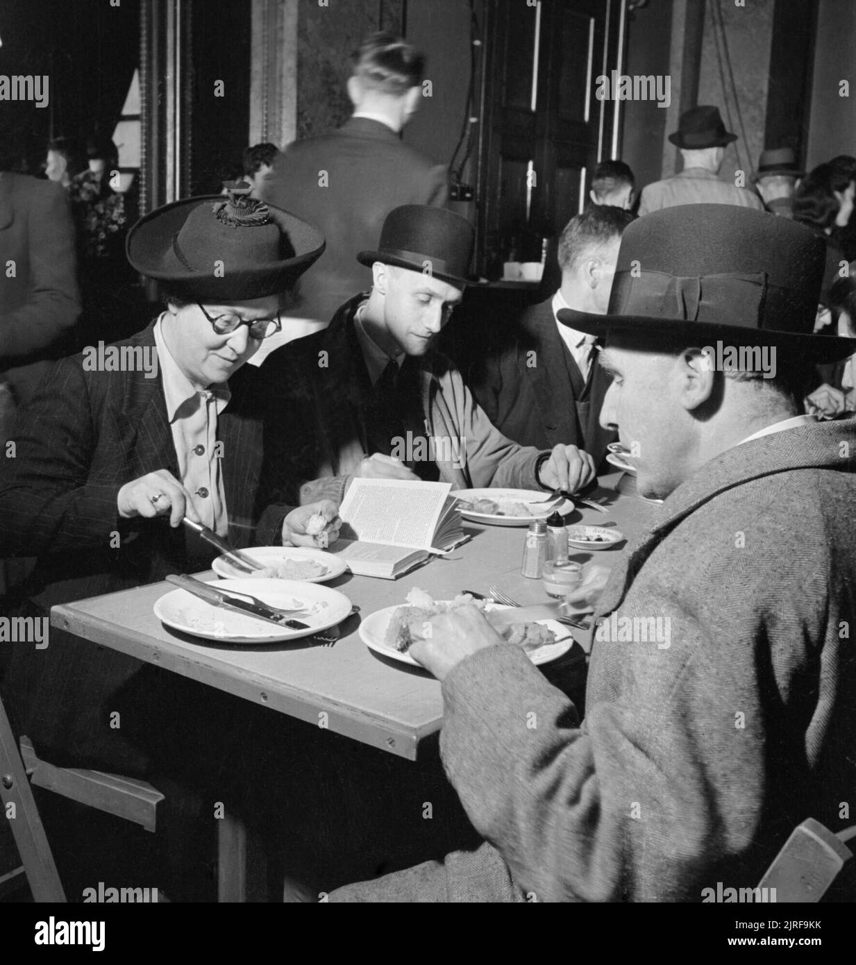 Les membres du public appréciant un repas au repas des londoniens à cantine Service de poissonnerie Hall, Londres, 12 octobre 1942. De nombreux différents types de personnes prenez un délicieux repas dans les Londoniens' Service repas à la cantine de poissonnerie Hall. Mme M Squires (à gauche) est un raccourci dactylo et son mari est dans la RAF. M. UN G Rosier (centre) est greffier en chef dans une entreprise de fabrication d'un coffre-fort pour le gouvernement. Monsieur W S Turner (à droite, l'appareil photo le plus proche) est un 62 ans greffier qui a servi dans la Brigade de carabiniers au cours de la Première Guerre mondiale. Banque D'Images