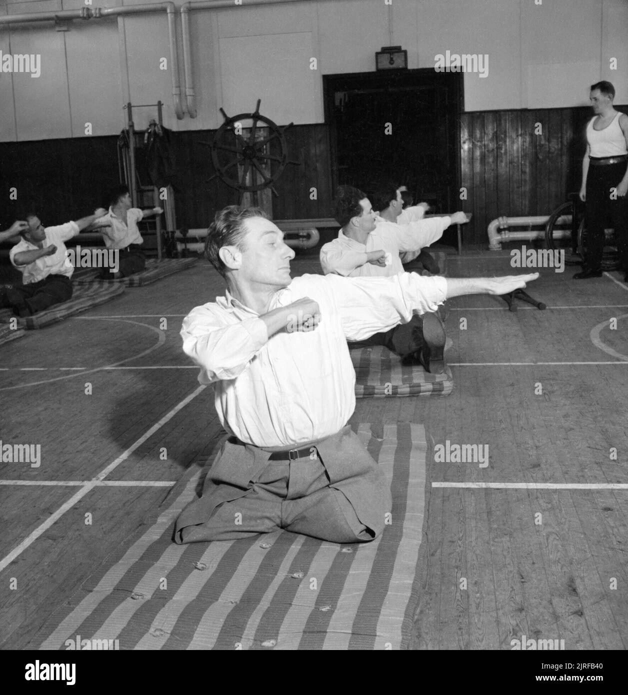 Réadaptation- le travail de l'hôpital Queen Mary, Roehampton, Londres, Angleterre, RU, 1944 patients à l'hôpital Queen Mary, Roehampton, qui ont perdu des membres, prendre part à une session de formation physique, dirigée par le Sergent Major Allen. Ils sont en tendant les bras et en tournant à la taille. Ces exercices sont destinés à renforcer la musculature des patients avant d'être équipée d'une prothèse. Banque D'Images