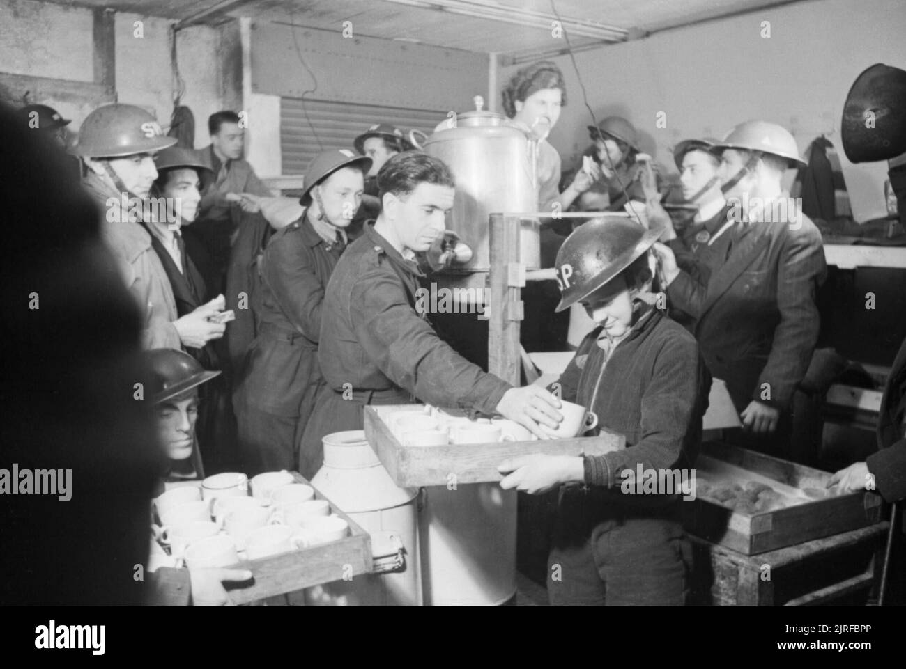 Le thé et les petits pains sont fournis par les travailleurs locaux de la sécurité aérienne (ARP) à d'autres travailleurs de la protection civile et civils dans ce sous-sol abri dans le sud-est de Londres en 1940. Banque D'Images