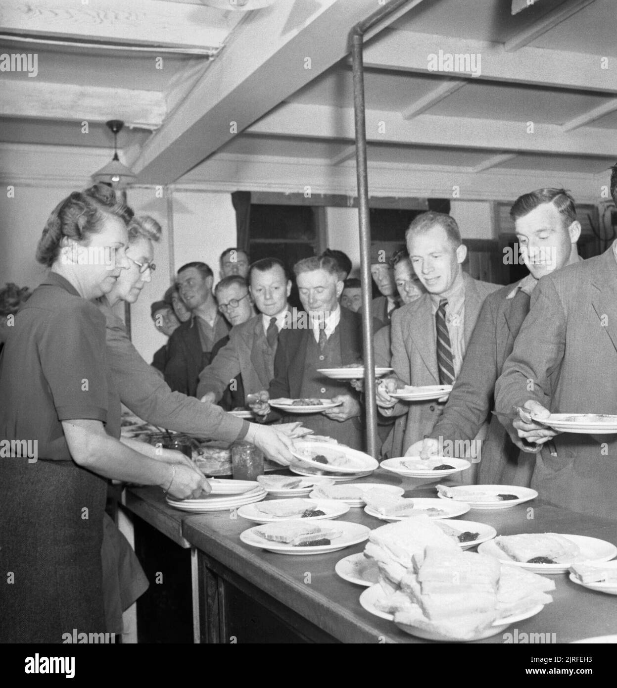 Blitz Repair Squad's Camp Londres- la vie quotidienne avec les équipes de réparation Blitz, Londres, Angleterre, RU, 1944 Les constructeurs de l'équipe de réparation 'Blitz' pour recueillir leur petit déjeuner de femmes du Women's Voluntary Service (WVS) dans le mess hut de leur camp dans le carré d'Onslow. Banque D'Images