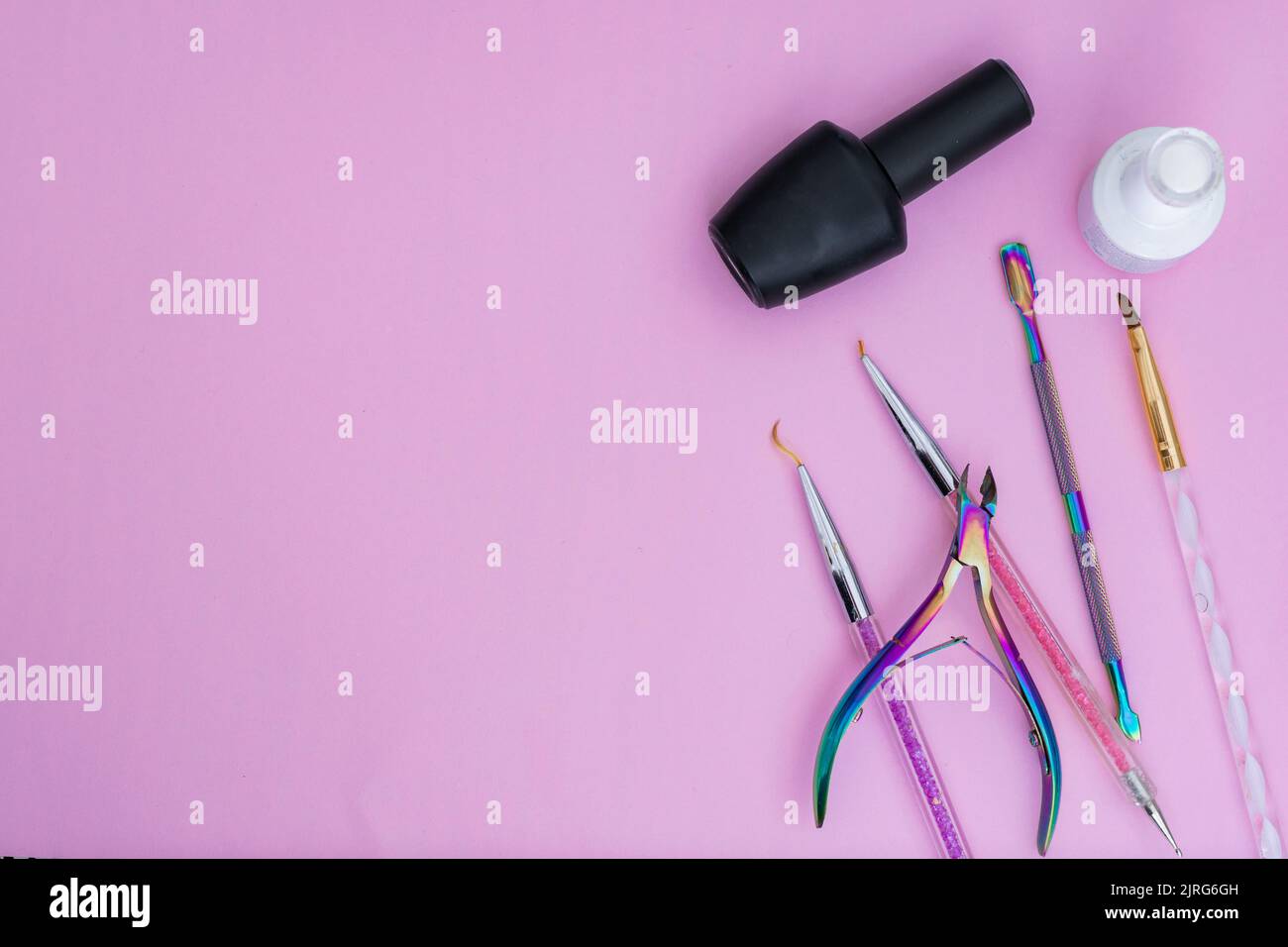 éléments de base pour une manucure, placés sur un fond rose. vernis à ongles noir et blanc, pinceaux de couleur, poussoir de cuticule et pince à cuticules articles pour Banque D'Images