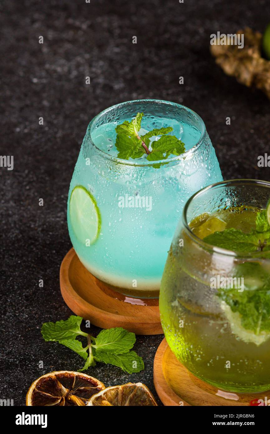 Plusieurs cocktails en verre avec cube de glace, fraise, lime, gingembre et feuille de menthe sur la table de texture Banque D'Images