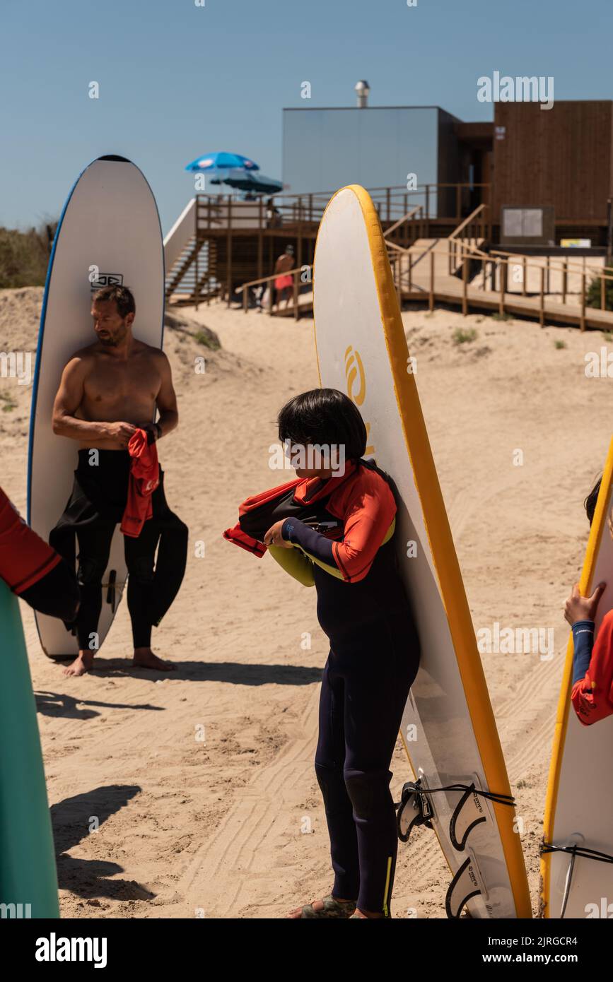 Aveiro, Portugal - 19 août 2022: Personnes avec des combinaisons et de ramasser des planches de surf à l'école de surf secreto. Banque D'Images