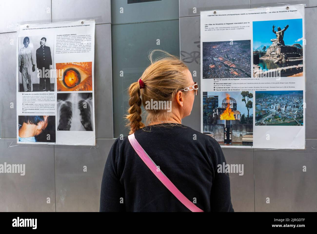Paris, France, femme vue par derrière, exposition, démonstration de l'ONG française contre le nucléaire (sortir du nucléaire) au Monument de la paix de Paris, photos de la bombe nucléaire de Nagasaki, affiches sur le mur Banque D'Images