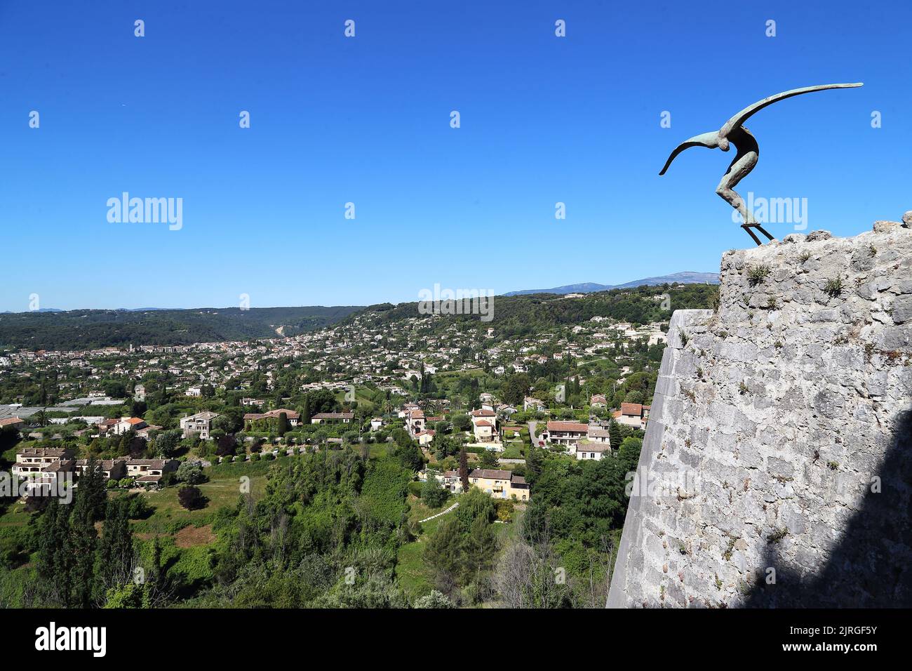 Il y a une sculpture sur les murs du village Saint-Paul de Vence et la vallée de la Provence s'étend au pied des murs en bois. Banque D'Images