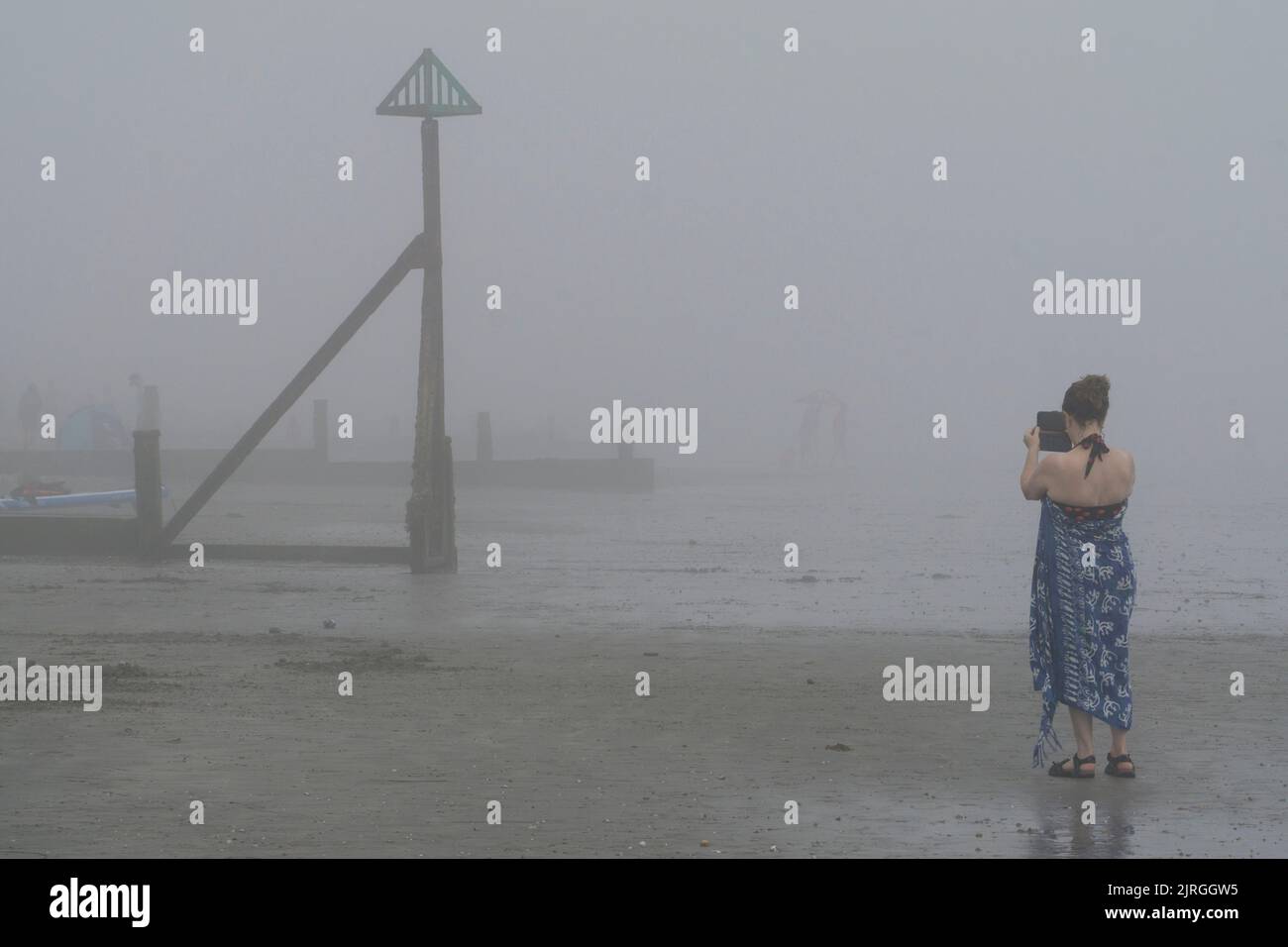 Météo au Royaume-Uni, West Sussex, 24 août 2022 : les amateurs de plage à East Wittering ont été surpris lorsqu'un après-midi ensoleillé a été coupé court par la brume de mer entrant et obscurcissant les vues habituelles de l'île de Wight. Mais il faut plus que du mauvais temps pour arrêter les nageurs, les surfeurs et les randonneurs à chiens, malgré l'atmosphère inquiétante. Anna Watson/Alay Live News Banque D'Images