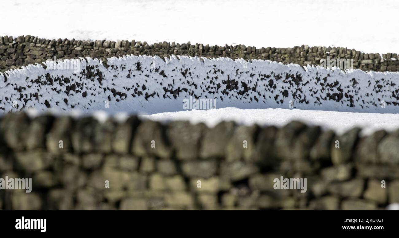 Image artistique de vieux murs de pierre blalé de neige par une journée ensoleillée au printemps, West Yorkshire, Angleterre, Royaume-Uni Banque D'Images