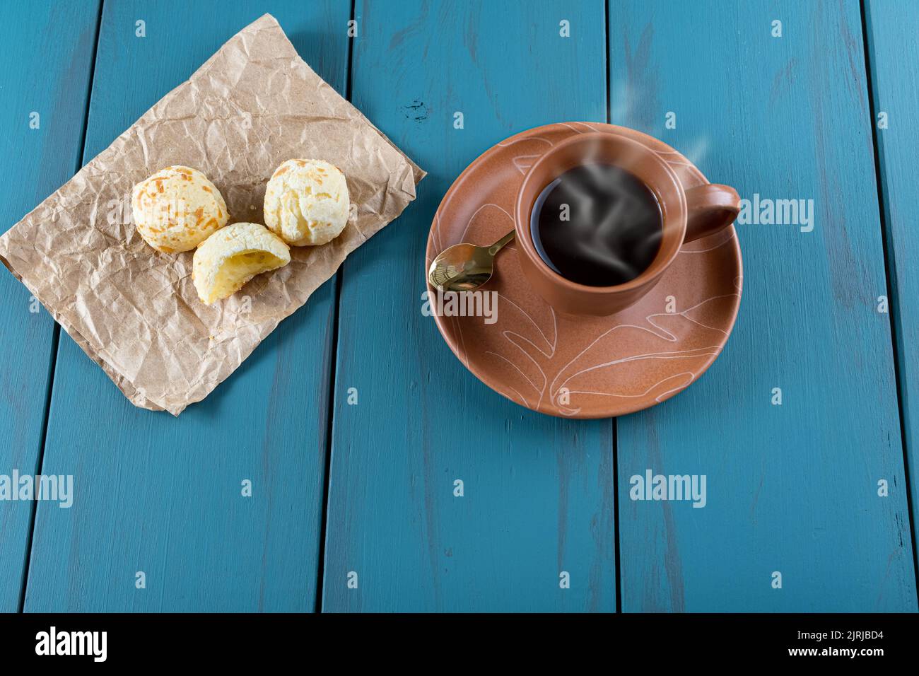 Pains au fromage brésilien à côté d'une tasse de café et d'une cuillère dorée vue de dessus. Banque D'Images