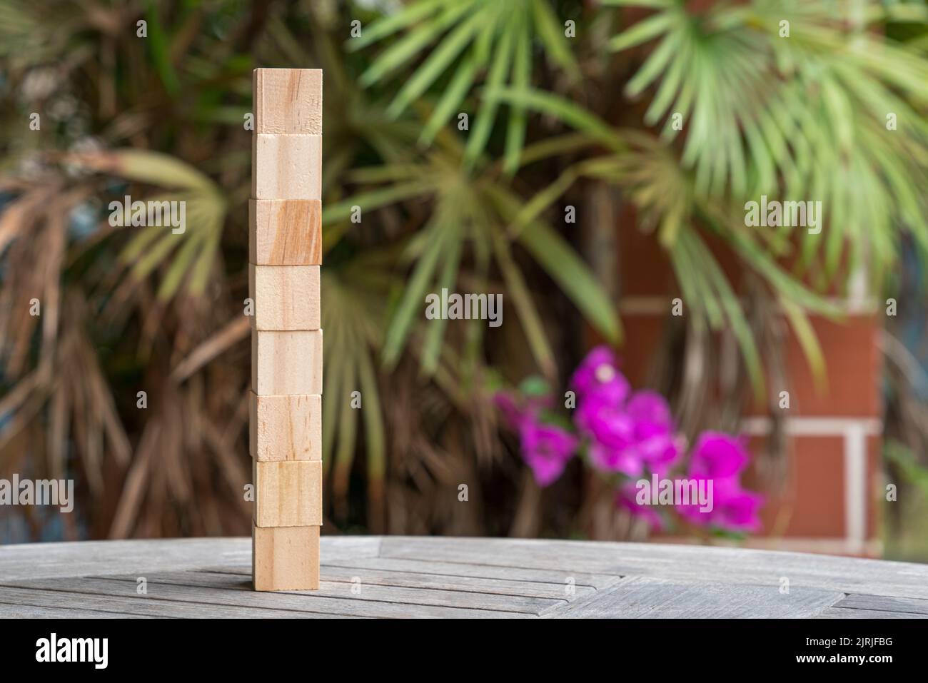 Huit cubes de blocs de bois vierges empilés en position verticale. Sur fond de nature et de jardin. Texte libre et modèle. Banque D'Images