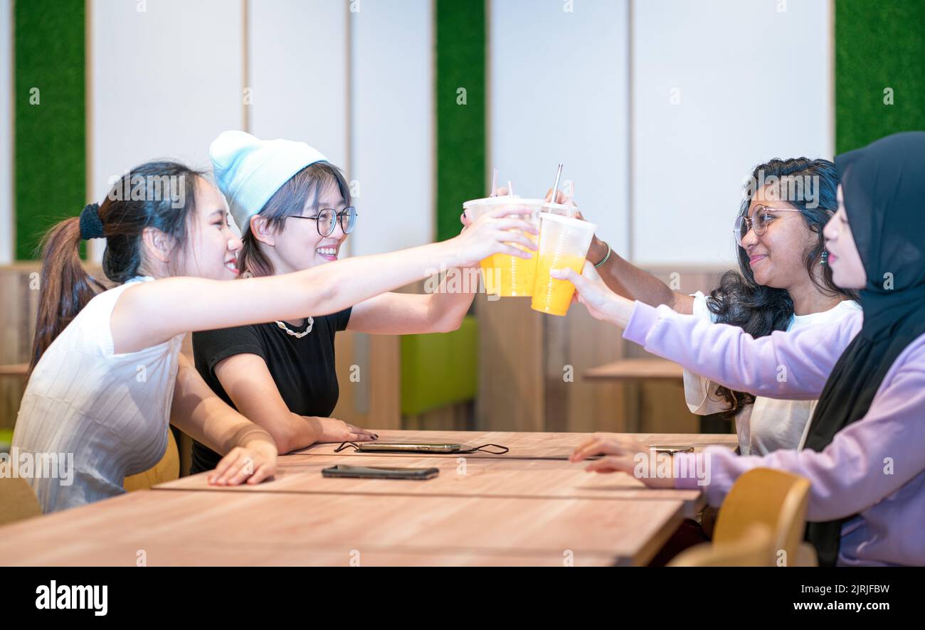 Groupe de filles amies multi-ethniques qui toasque des boissons dans un restaurant. Banque D'Images