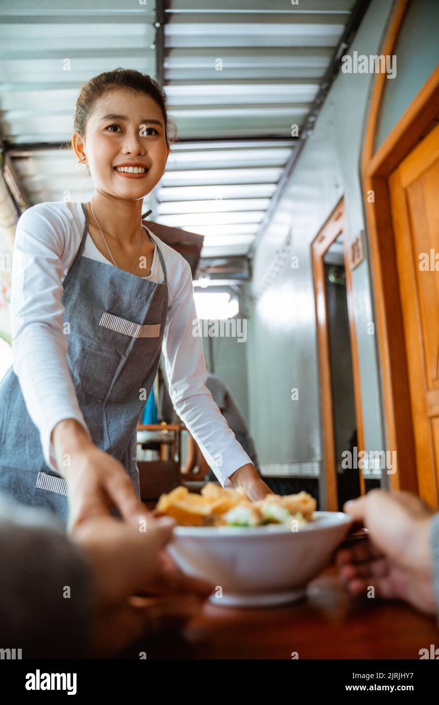 un serveur servant un bol de nouilles de poulet Banque D'Images