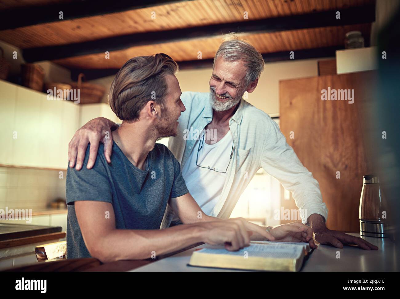 Tout le monde a besoin d'un mentor spirituel. Un père et un fils qui étudient la Bible ensemble à la maison. Banque D'Images