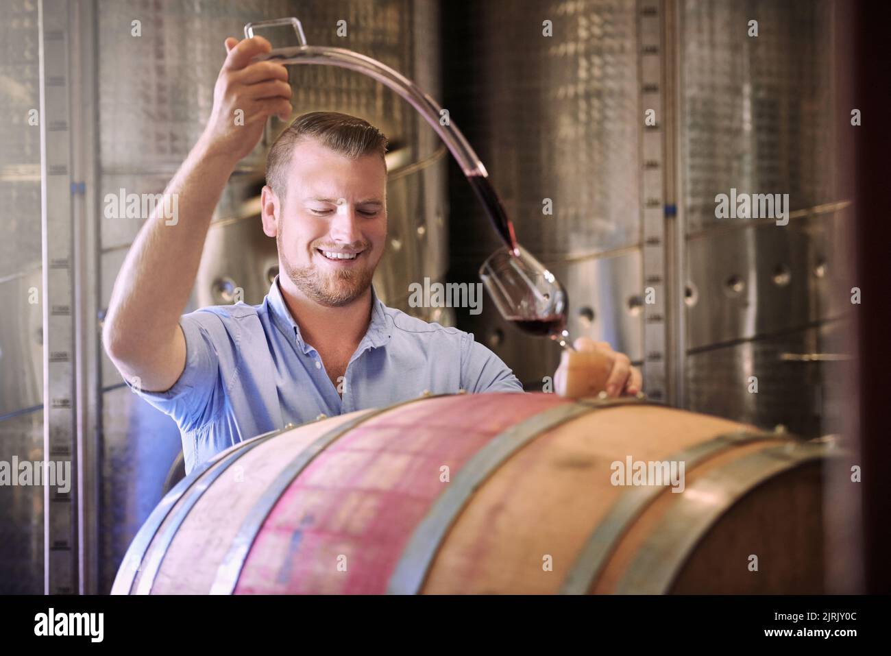 Fait à la main pour des moments spéciaux. Un sommelier verse un verre de vin directement dans le fût. Banque D'Images