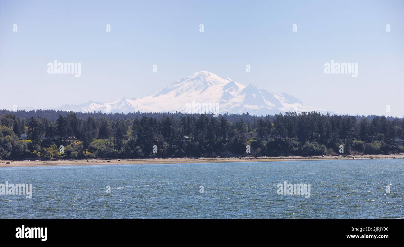 Maisons au bord de la plage sur la côte ouest de l'océan Pacifique avec montagne enneigée Banque D'Images
