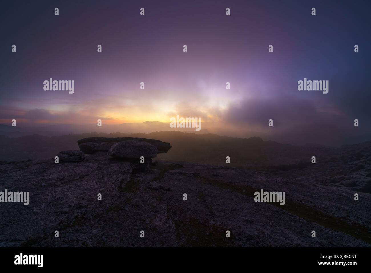 Paysage au lever du soleil sur quelques montagnes rocheuses sous un ciel avec des nuages bas Banque D'Images