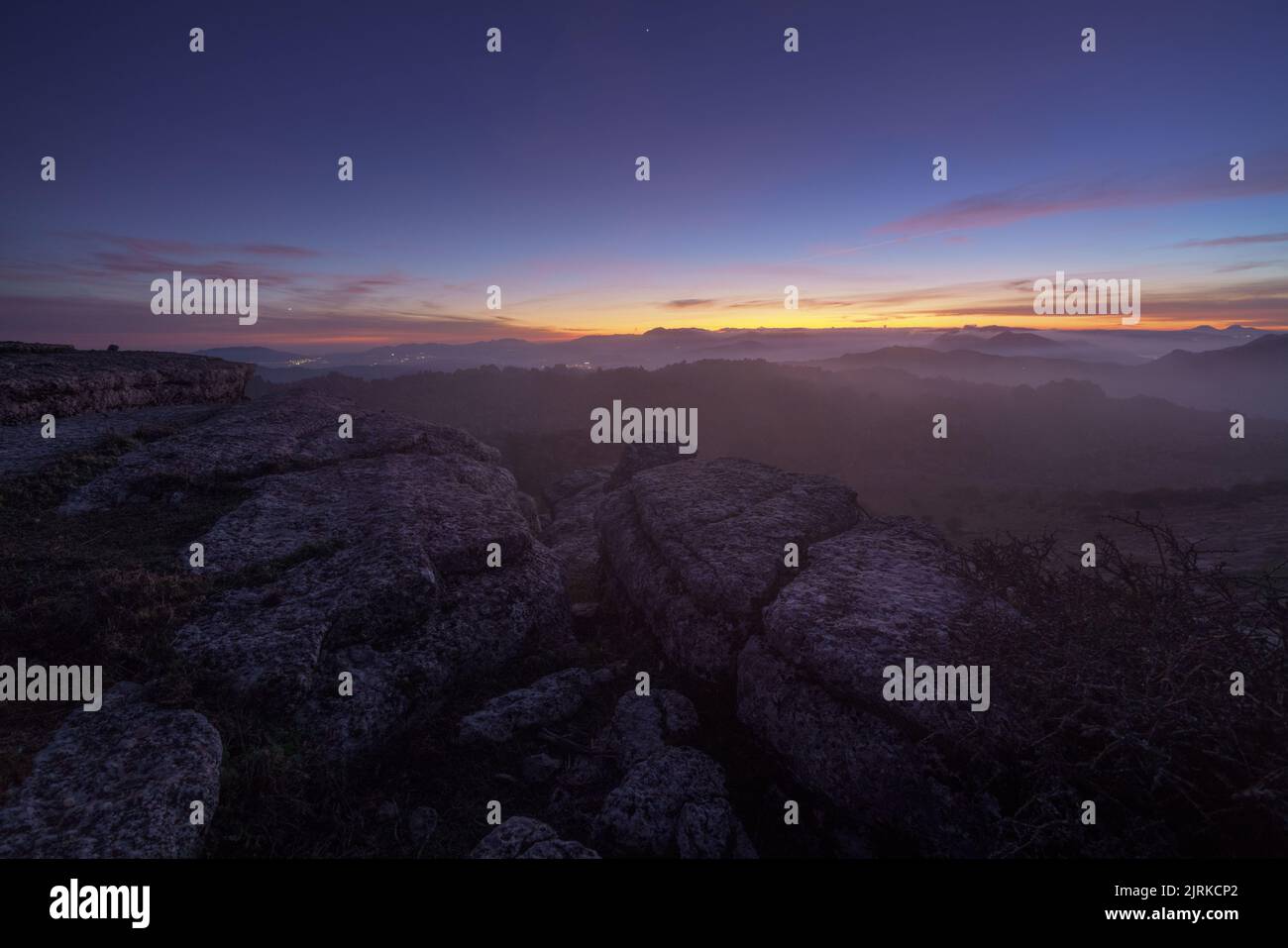 Paysage au lever du soleil sur quelques montagnes rocheuses sous un ciel avec des nuages bas Banque D'Images
