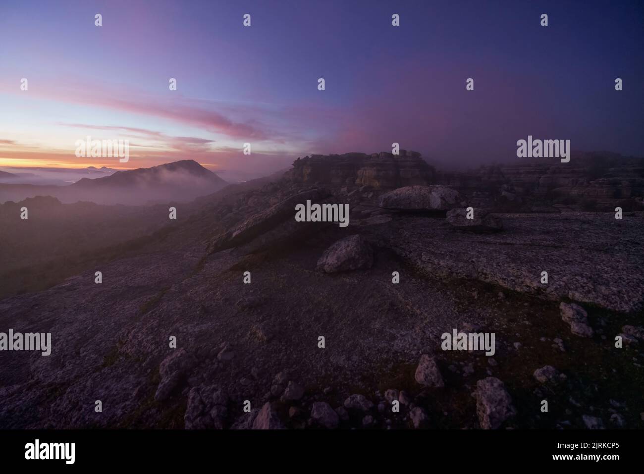 Paysage au lever du soleil sur quelques montagnes rocheuses sous un ciel avec des nuages bas Banque D'Images