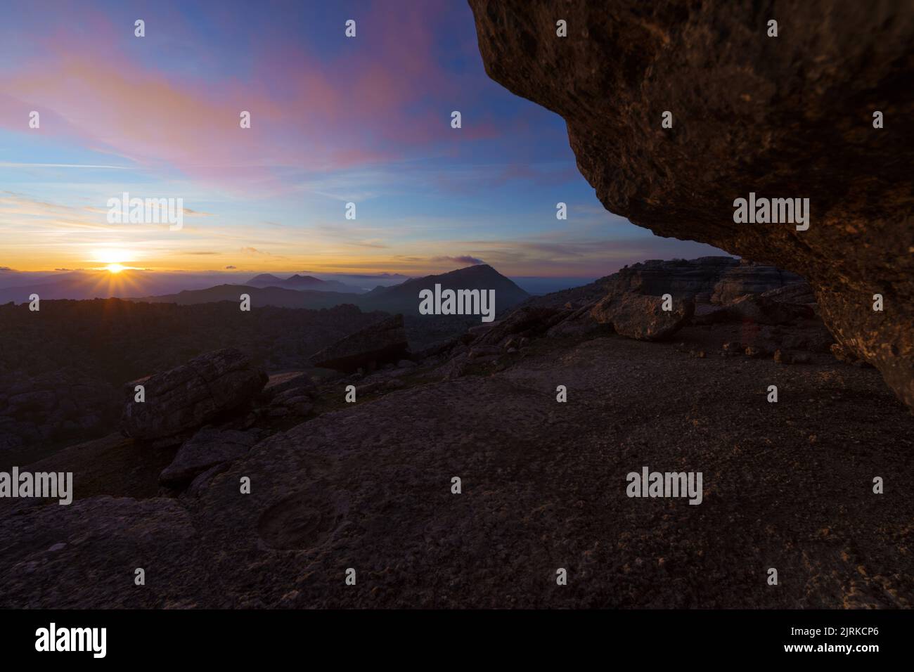 Paysage au lever du soleil sur quelques montagnes rocheuses sous un ciel avec des nuages bas Banque D'Images