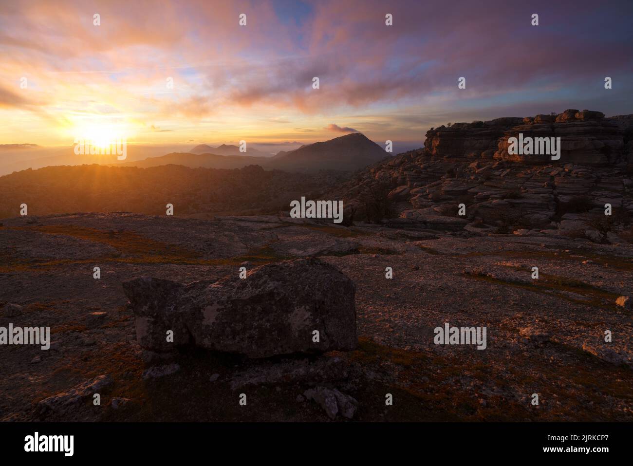 Paysage au lever du soleil sur quelques montagnes rocheuses sous un ciel avec des nuages bas Banque D'Images
