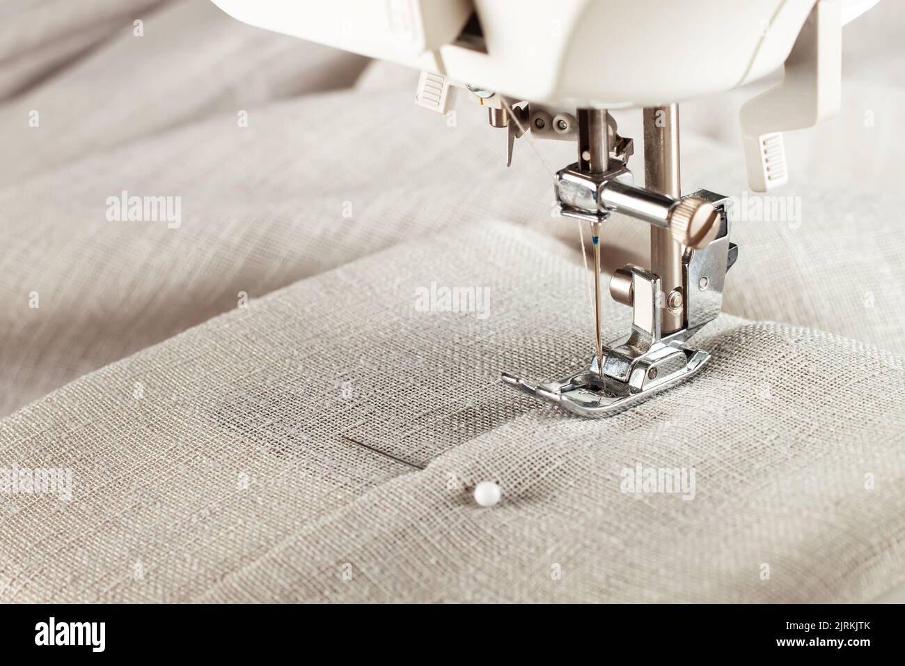 Machine à coudre moderne presser le pied avec le tissu et le fil de lin, gros plan, espace de copie. Processus de couture vêtements, rideaux, tissus d'ameublement. Affaires, passe-temps, h Banque D'Images