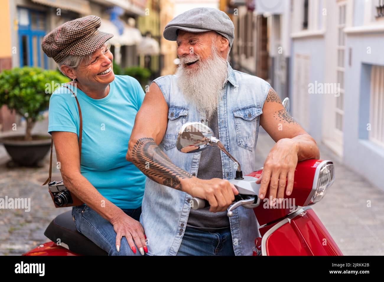 Vue latérale d'un couple senior moderne en moto tout en traversant la ville Banque D'Images