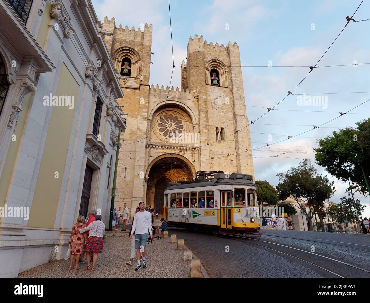 Cathédrale Saint Mary Major alias Cathédrale de Lisbonne alias Sé de Lisboa. Un tramway passe devant la cathédrale tandis que les touristes se promèdonnent dans la rue. Banque D'Images