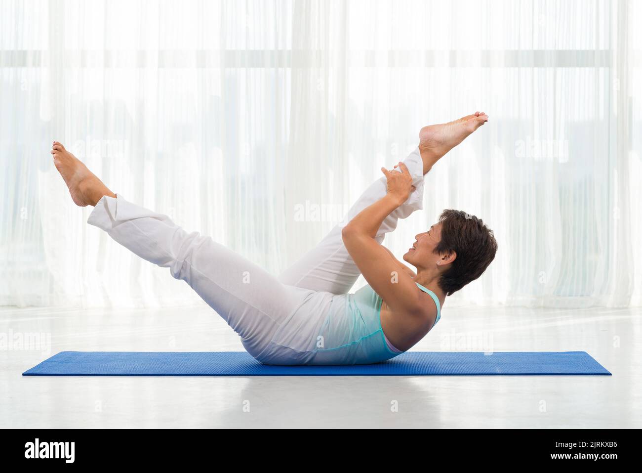 Femme japonaise mature pratiquant le yoga dans un studio de retraite Banque D'Images