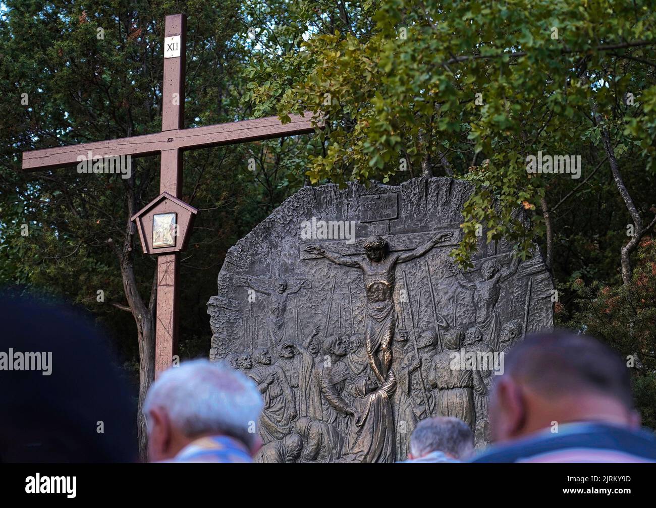 La douzième station du chemin de la Croix (« Jésus meurt sur la Croix ») et certains croyants catholiques priant alors qu'ils grimpent sur le Mont Križevac (Medjugorje) Banque D'Images