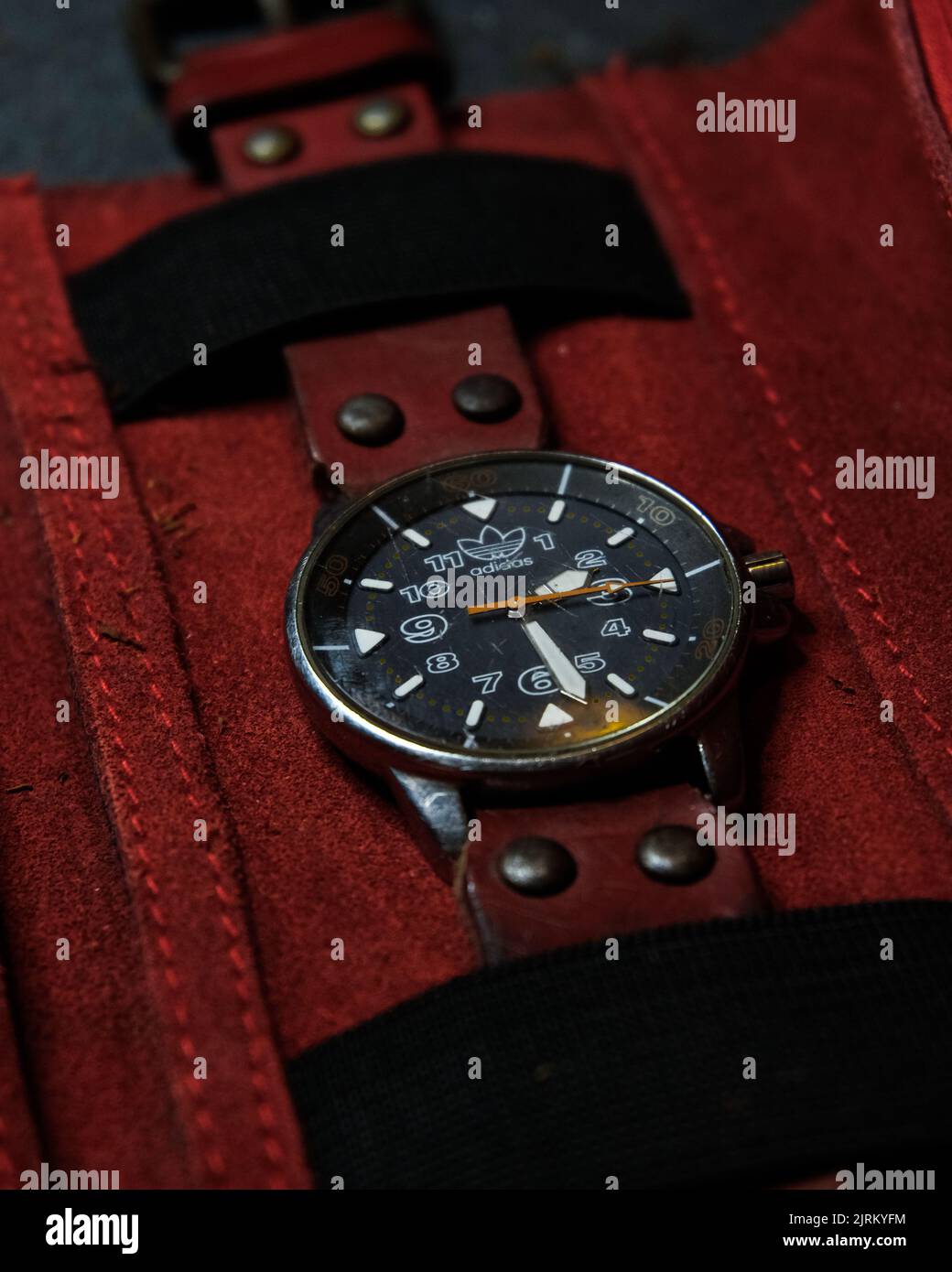 Un gros plan vertical de la montre originale Adidas vintage sur fond de tissu rouge Banque D'Images