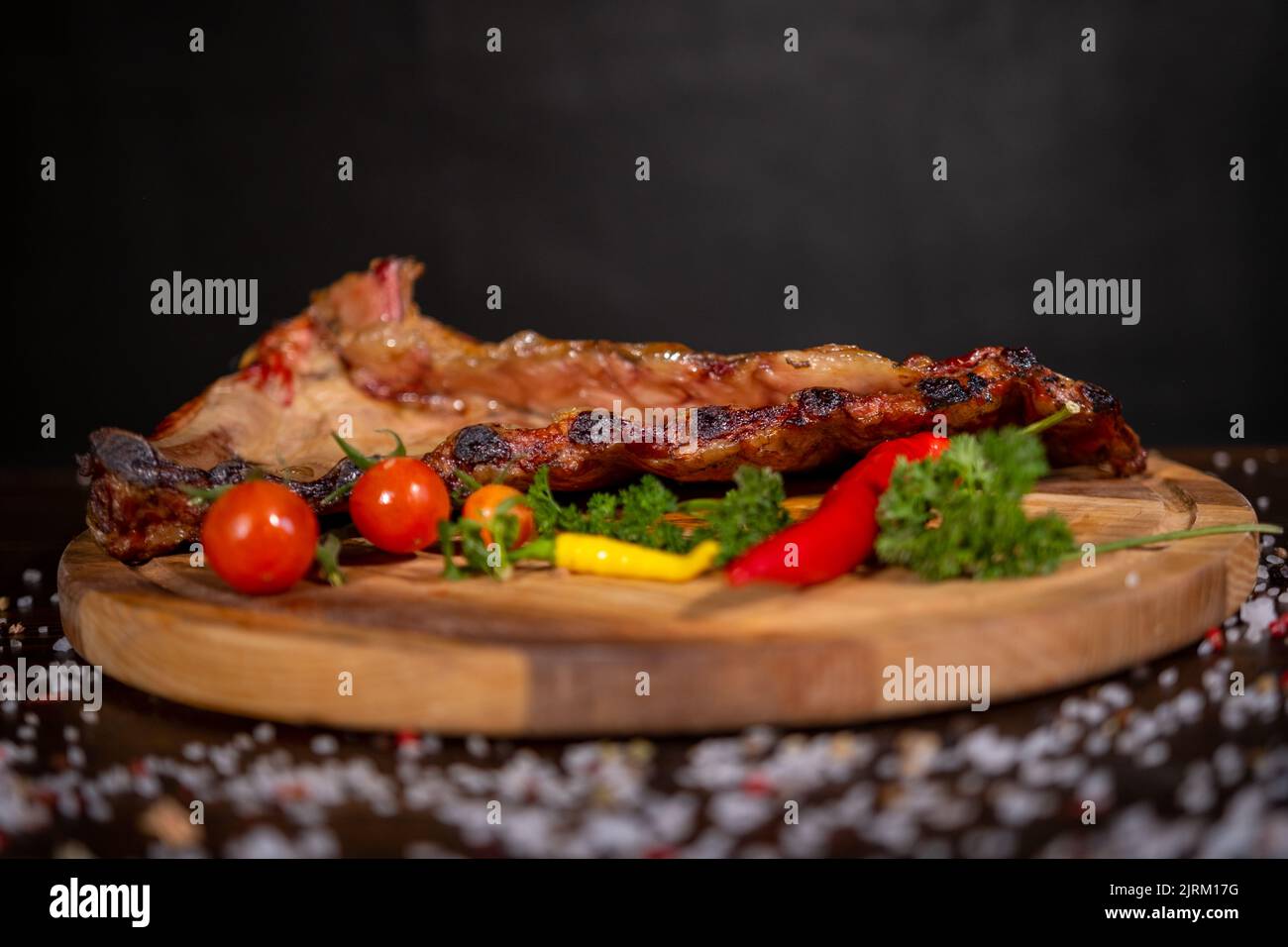Gros plan du porc grillé à la sauce barbecue et caramélisées dans du miel. Délicieux en-cas à la bière sur une planche en bois pour la production de béton sur fond sombre Banque D'Images