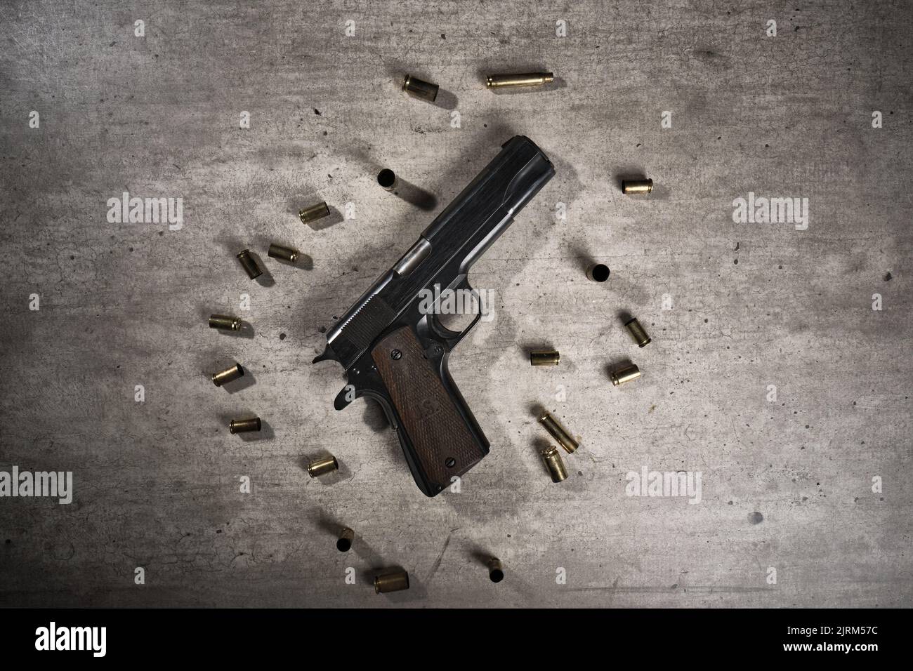 Un pistolet noir sur fond gris avec des cartouches usagées autour Banque D'Images
