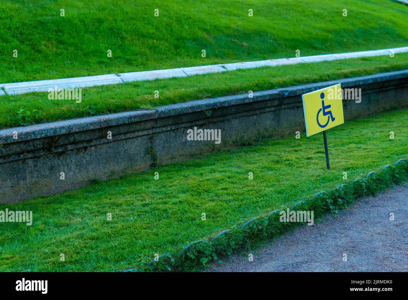 RUSSIE, PETERSBOURG - 19 AOÛT 2022 : panneau pour personnes handicapées herbe fauteuil roulant jardin handicap chemin symbole, concept d'avertissement d'accès dans la route et siège non valide Banque D'Images