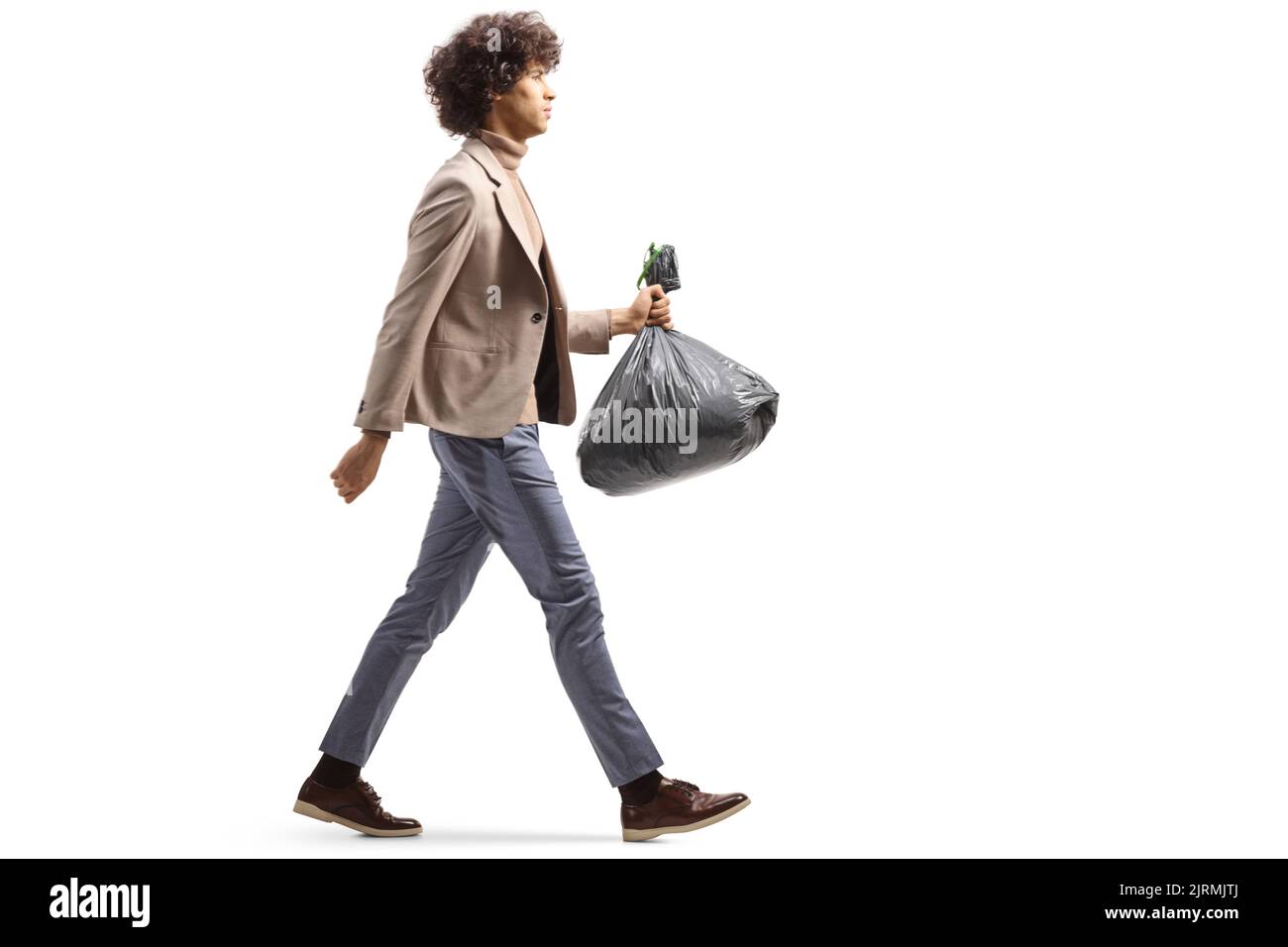 Photo pleine longueur d'un grand jeune homme marchant et portant un sac poubelle en plastique isolé sur fond blanc Banque D'Images