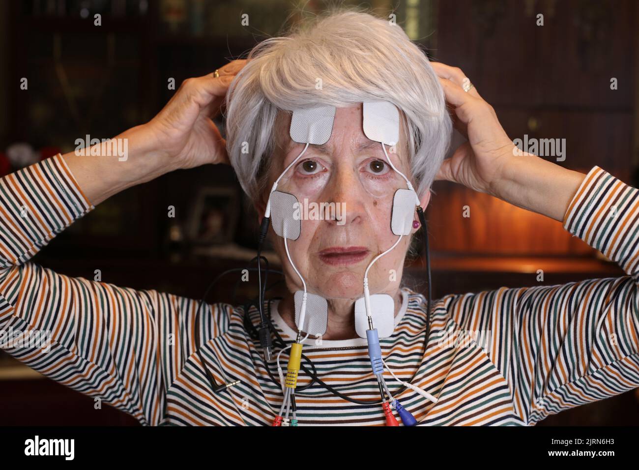 Lady essayant thérapie alternative avec électrostimulation Banque D'Images