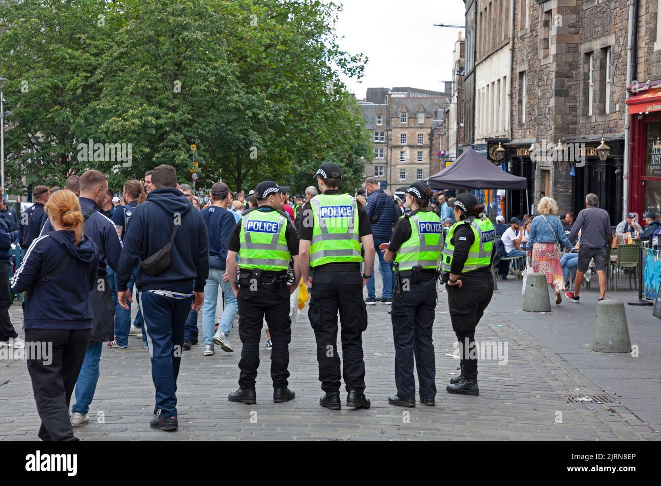 Centre-ville d'Edimbourg, Ecosse, Royaume-Uni. 25th août 2022. Nuageux mais doux, 19 degrés centigrades pour les fans du FC Zurich qui se sont réunis entourés par des policiers dans le Grassmarket désordonné pour socialiser paisiblement avant le match de ce soir avec le cœur du Midlothian. De plus, des foules plus petites dans le Royal Mile pour les artistes de rue. Photo : des policiers dans un caucus qui rendent leur présence évidente aux fans paisibles du FC Zurich qui prennent un verre. Credit: ArchWhite/alamy Live news. Banque D'Images