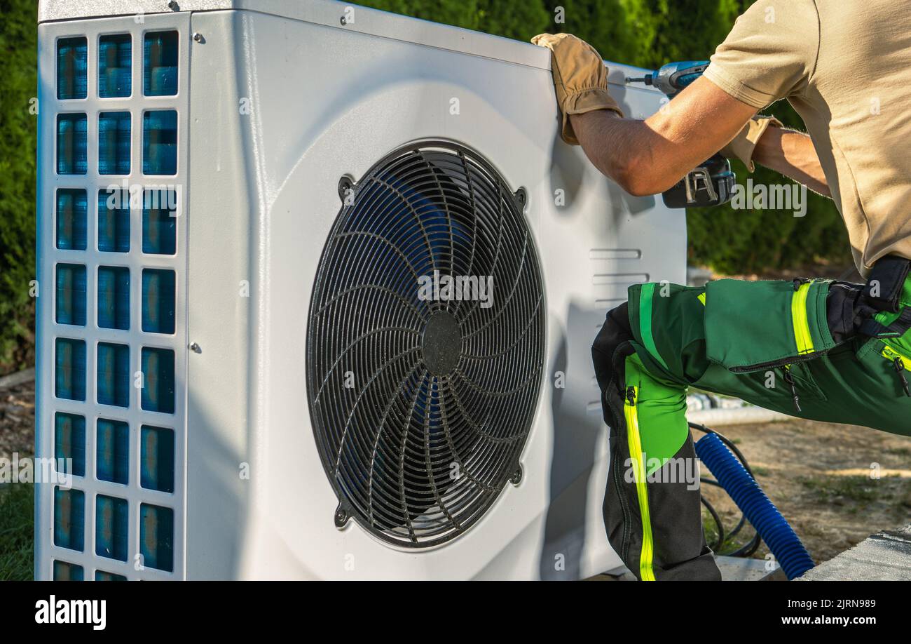 Travailleur de CVC caucasien installant une pompe à chaleur électrique moderne et à économie d'énergie. Banque D'Images