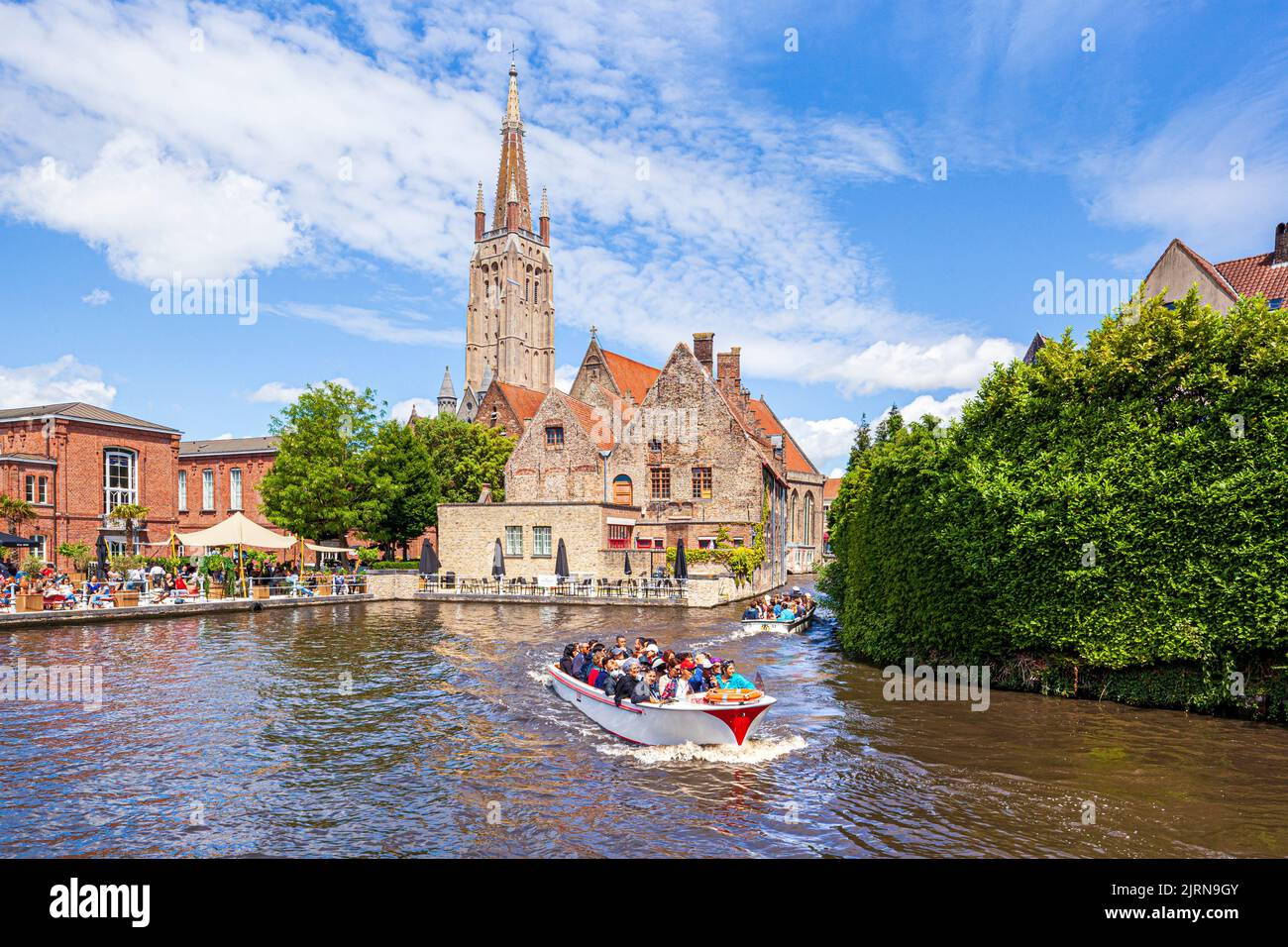 La flèche de l'église notre-Dame (onze-Lieve-Vrouwekerk) surplombant l'hôpital St Johns (Sint-Janshospitaal) et les touristes profitant d'une excursion en bateau le Th Banque D'Images