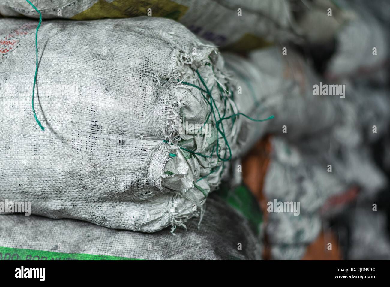 vue détaillée des sacs blancs pleins de matériaux et de produits à l'intérieur d'un entrepôt, attaché avec des rubans verts ou cabuyas. sacs pleins de charbon de bois Banque D'Images