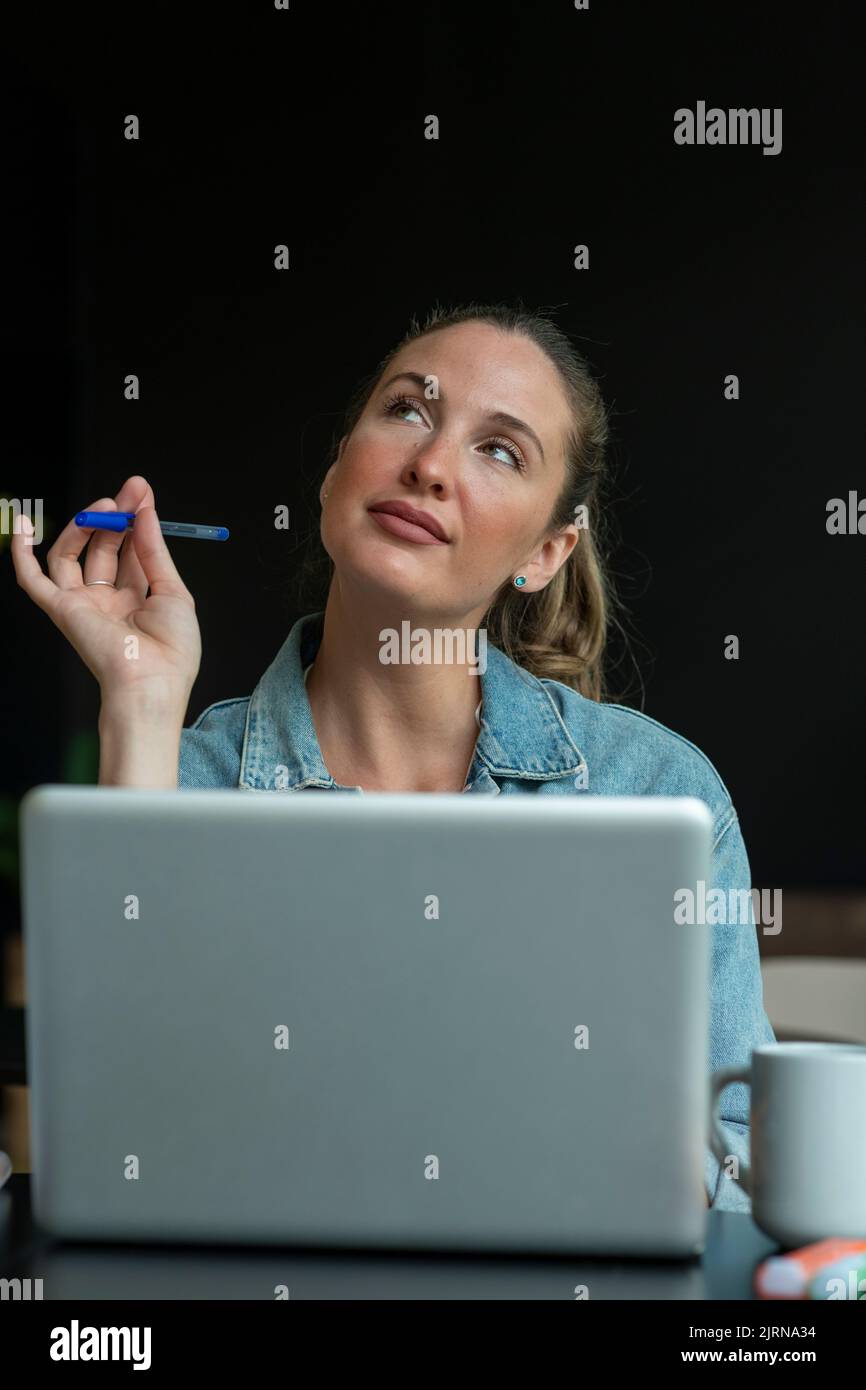 Jeune femme travaillant au bureau dans une humeur de réflexion - photo de stock Banque D'Images