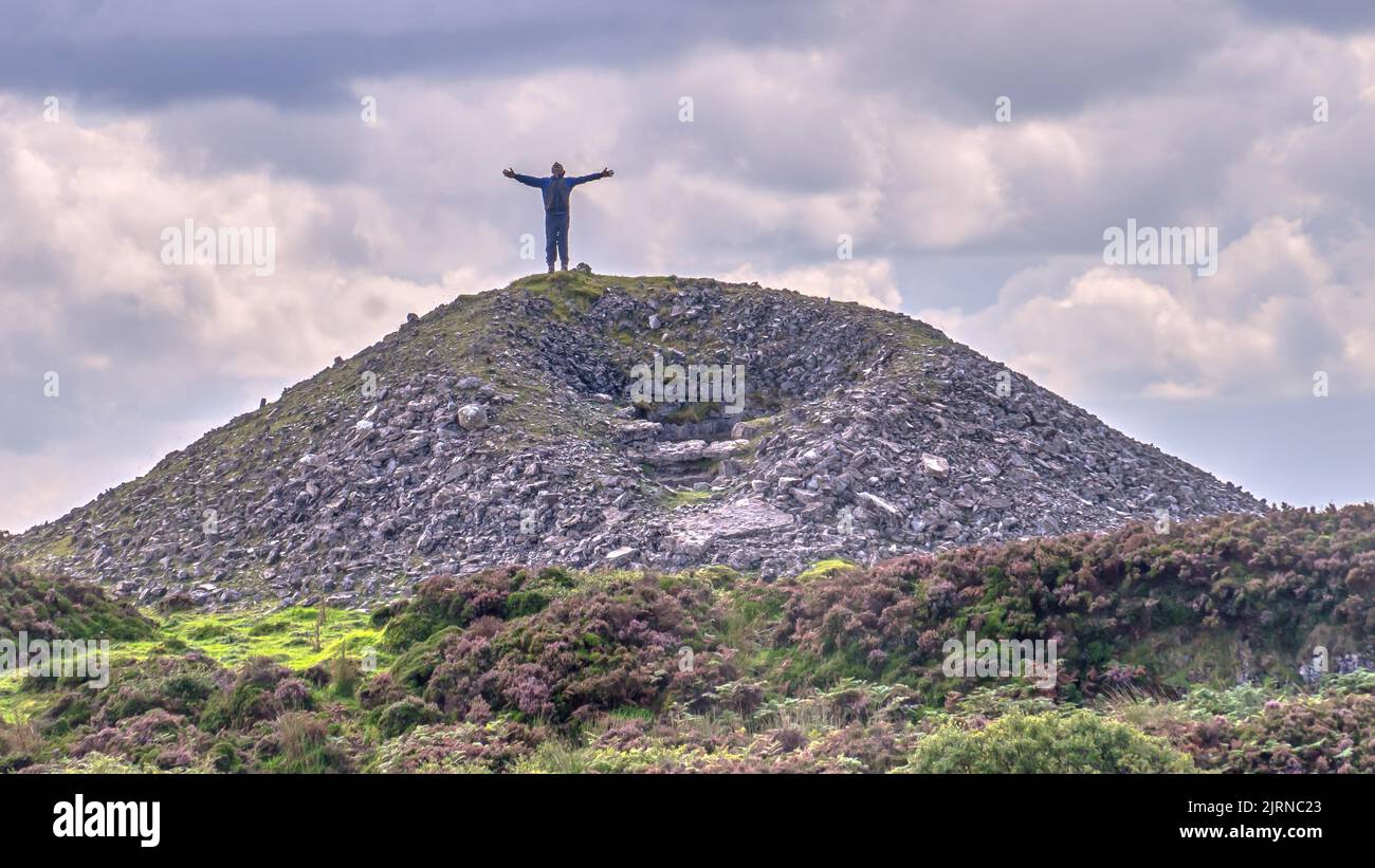 Silhouette d'un homme debout au-dessus d'une montagne avec les bras étirés. Banque D'Images