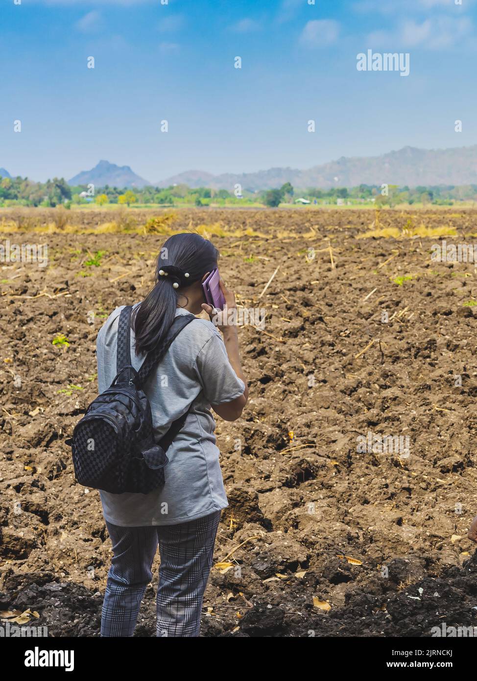 Vue arrière de la femme de routard asiatique utiliser le téléphone pour parler des affaires pour planifier l'agriculture dans le désert. Les agricultrices consultent les propriétaires fonciers pour cultiver les cultures Banque D'Images