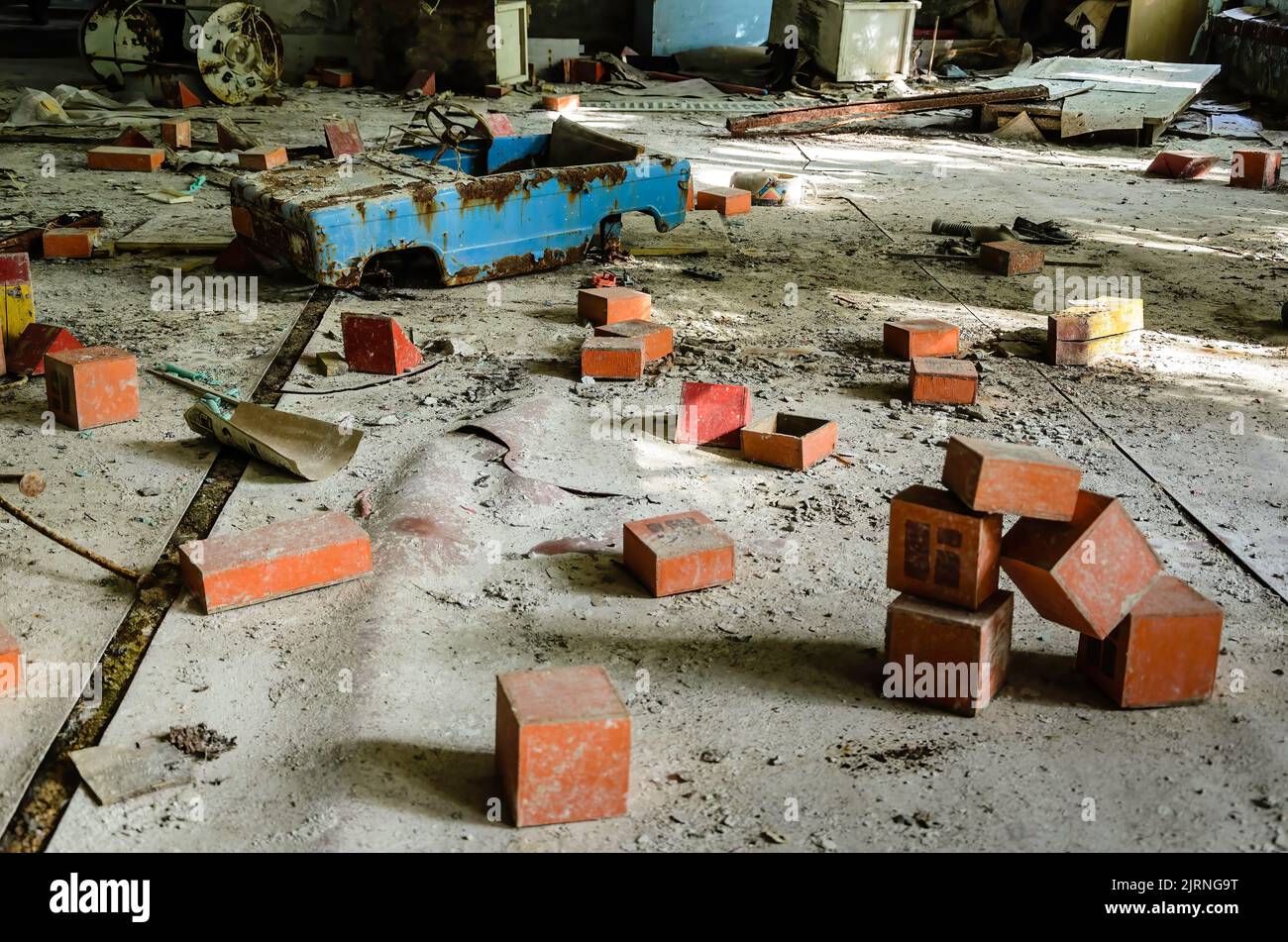 Salle de jeux dans un bâtiment de Prypiat. Des cubes rouges et une voiture bleue cassée pour les enfants sont répartis dans toute la pièce. Zone d'exclusion de Tchernobyl, Ukraine Banque D'Images