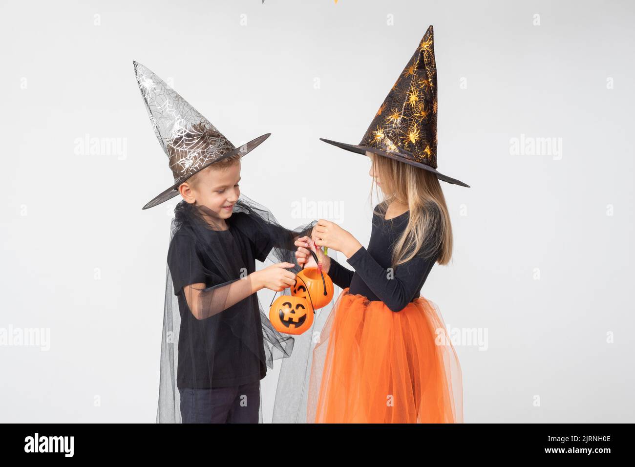 Halloween pour enfants. Une belle fille dans un costume de sorcière et un garçon dans un costume de magicien prendre des bonbons d'un panier en forme de lanterne de Jack. Enfant h Banque D'Images