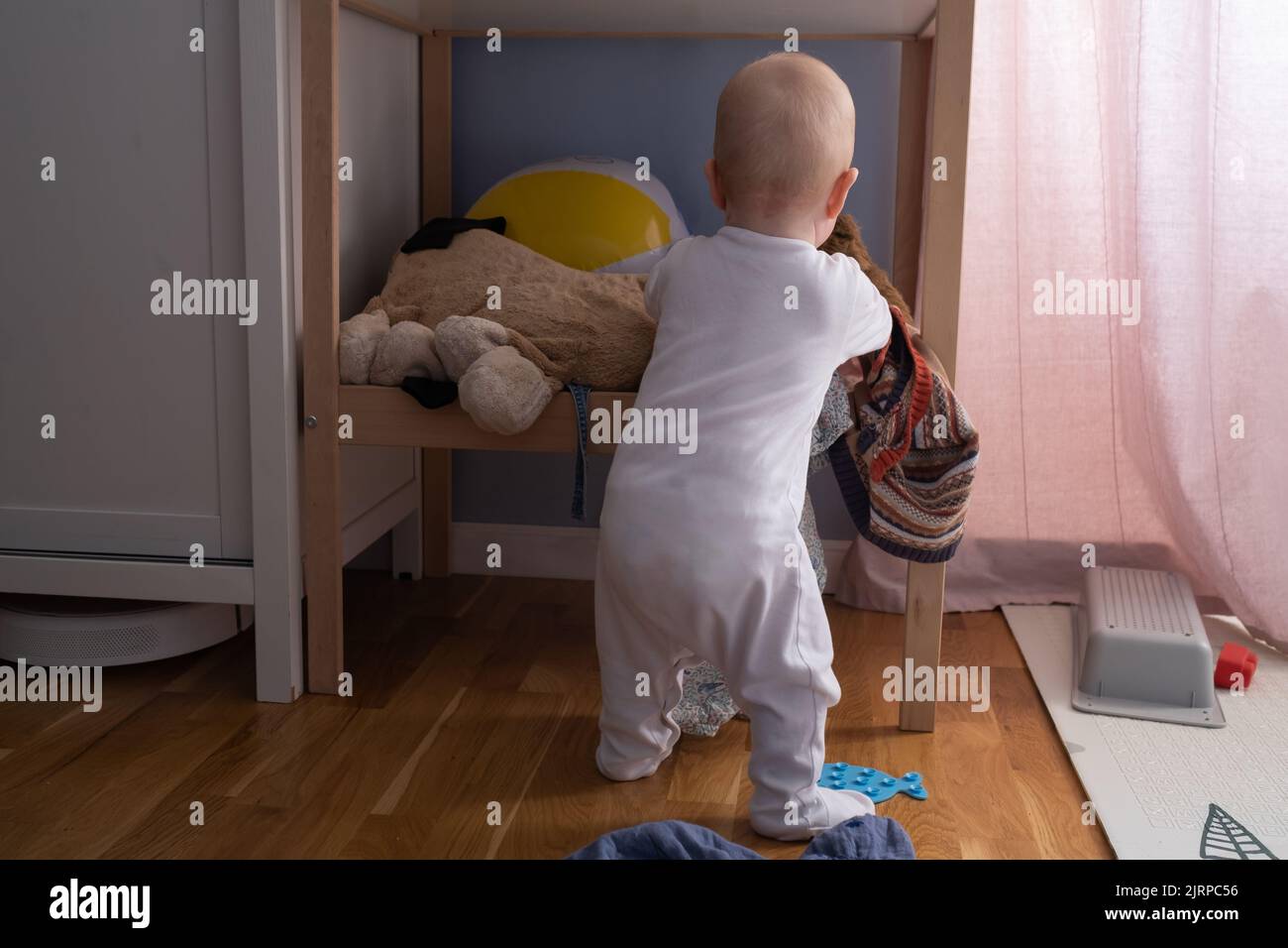 Bébé caucasien jouant avec des jouets les dispersant aroung. Banque D'Images