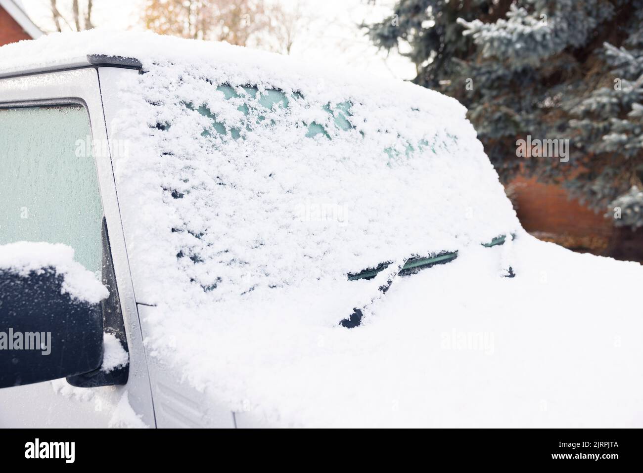 Neige et glace recouvrant un pare-brise ou un pare-brise de voiture, garée sur une allée à l'extérieur d'une maison, Royaume-Uni Banque D'Images