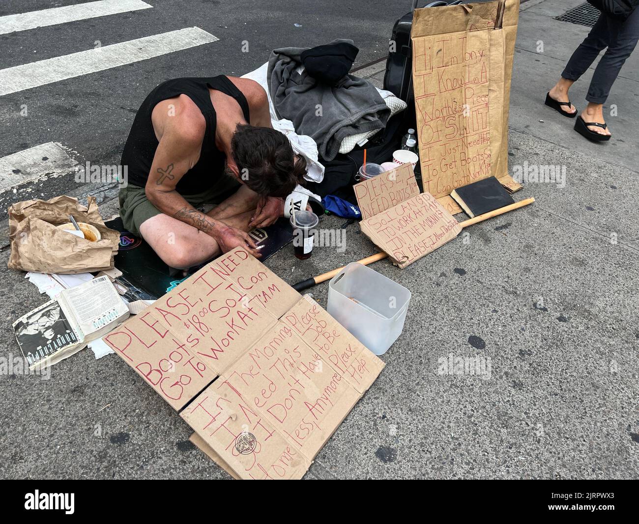 Un homme sans domicile communique par écrit avec le public pour obtenir de l'aide sur le trottoir près de Penn Station à Manhattan, New York. Banque D'Images