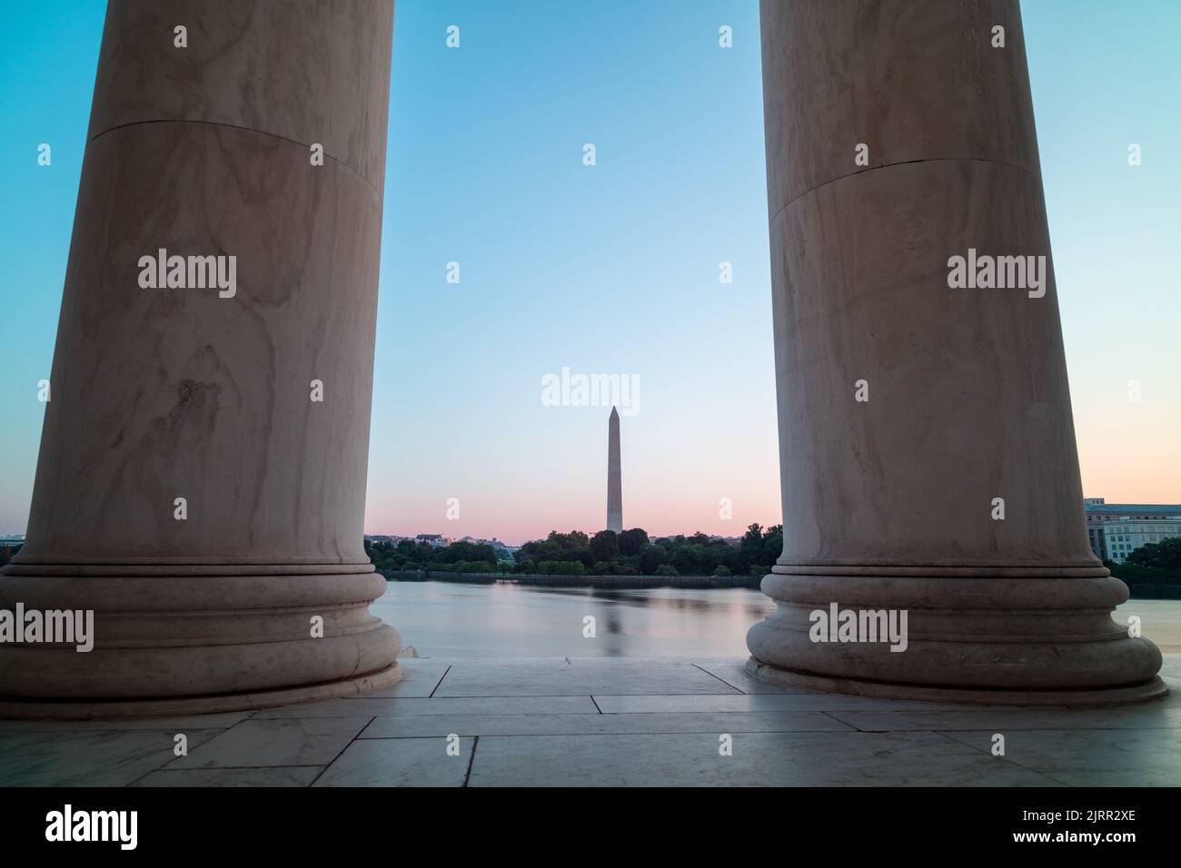 Le Washington Monument et la Maison Blanche sont vus de l'autre côté du bassin de Tidal, encadré par deux colonnes dans le Jefferson Memorial. Lever du soleil en été. Banque D'Images