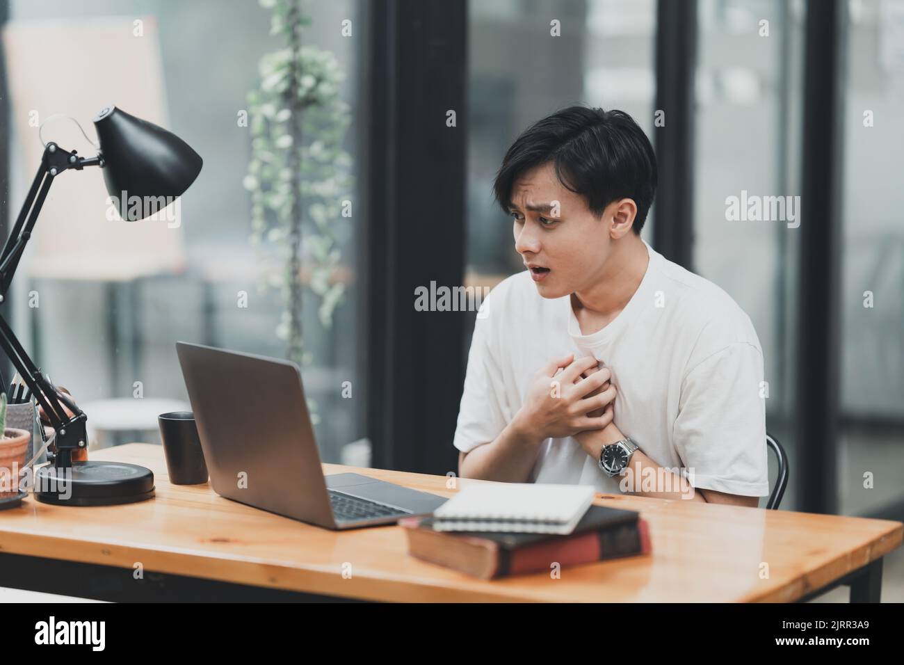 Un homme asiatique utilisant un ordinateur portable choquant alors qu'il a une mauvaise nouvelle Banque D'Images
